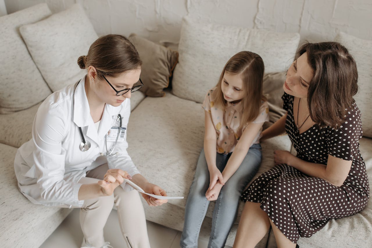 Doctor explaining diagnosis to mother and daughter in office.